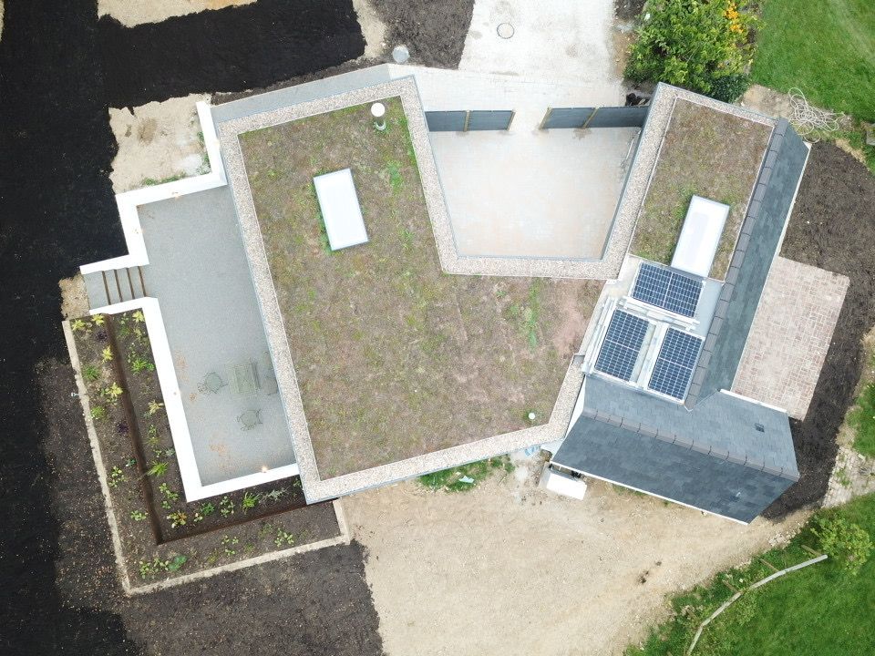 Drone view of the finished Bolney home with sedum green roof, solar panels and landscaped courtyards