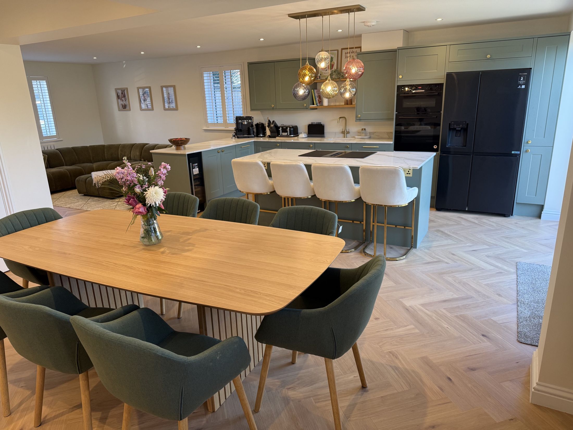 Dining table under copper pendant lights, kitchen beyond