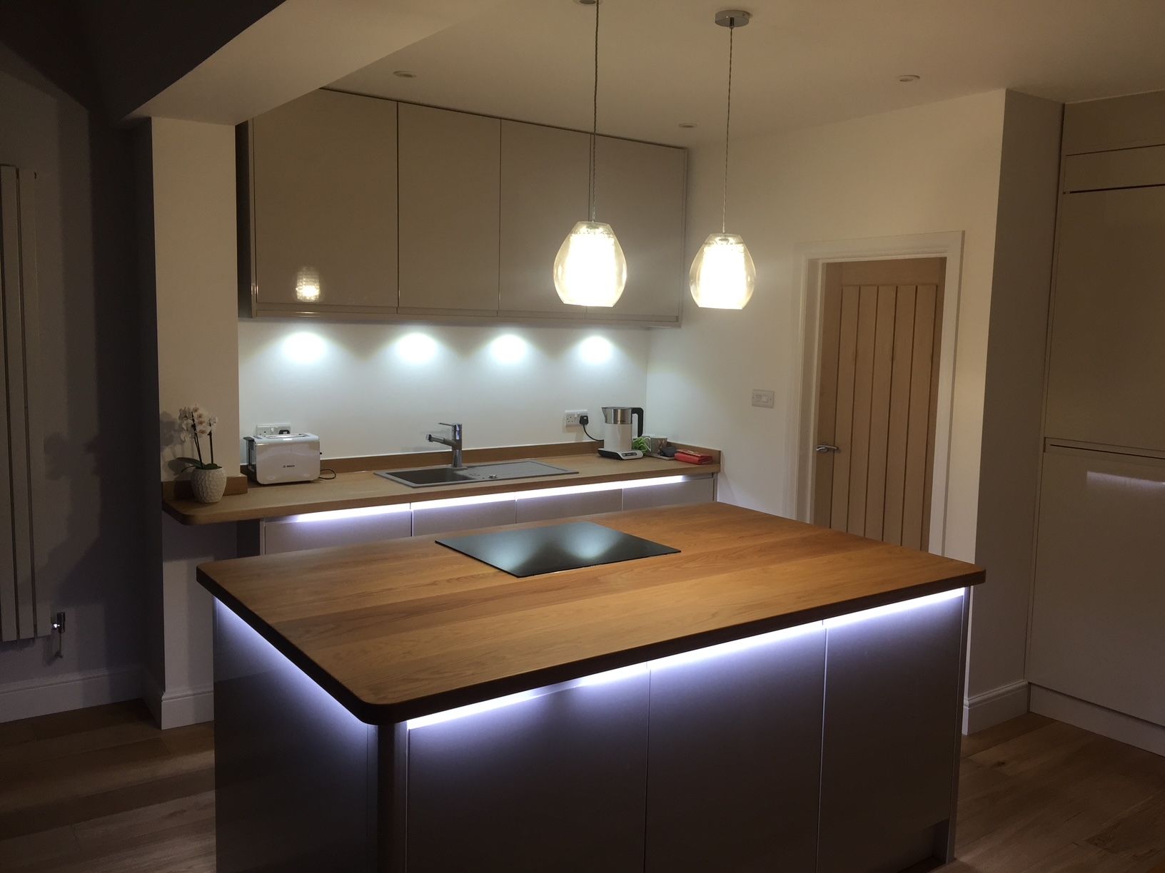 Kitchen island with oak worktop and under-lighting, pendant lights above