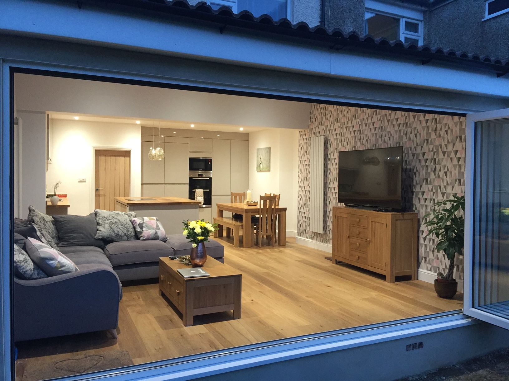 Open-plan kitchen, dining and living room seen from the garden through open bifold doors